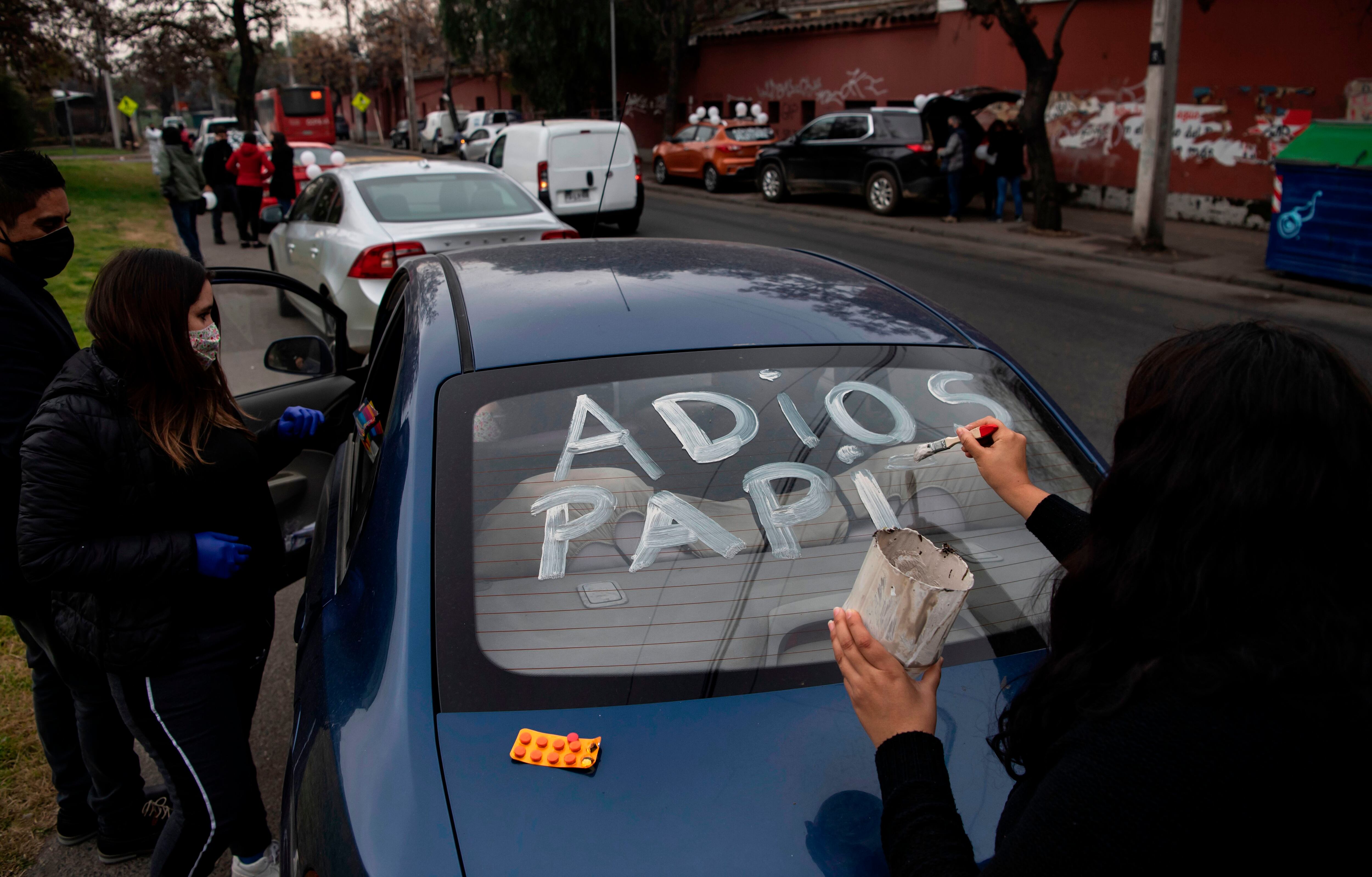 A woman writes "Goodbye daddy" on the car window while waiting to receive his coffin, outside the San Jose Public Hospital morgue, in Santiago, on June 22, 2020 amid the new coronavirus pandemic. - Chile nearly doubled its reported coronavirus death toll Saturday to more than 7,000 under a new tallying method that includes probable fatalities from COVID-19. (Photo by MARTIN BERNETTI / AFP) (Photo by MARTIN BERNETTI/AFP via Getty Images)