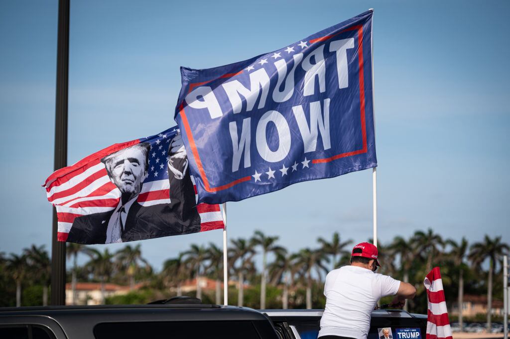 Un seguidor de Donald Trump con banderas del candidato presidencial en la localidad de Palm Beach en Florida.