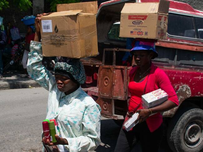 Personas llevan sus compras en unas cajas en la ciudad de Puerto Príncipe en Haití.