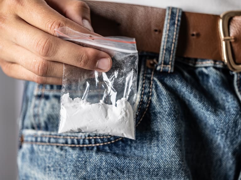 The hand selects a package with a drug - cocaine in the back pocket of jeans