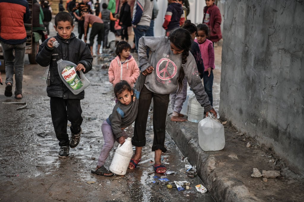 Un grupo de niños palestinos llevan envases con agua, en medio de la guerra que lleva adelante Israel contra la Franja de Gaza en Palestina.