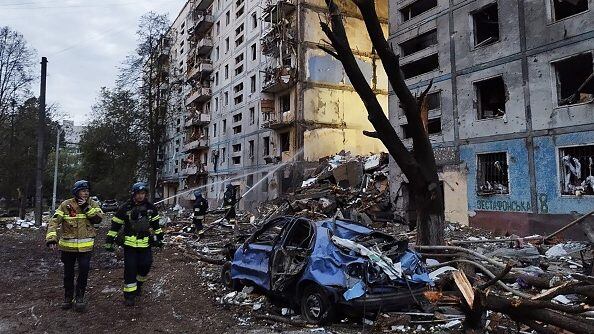 TOPSHOT - Rescuers walk past a residential building damaged after a strike in Zaporizhzhia, amid the Russian invasion of Ukraine on October 9, 2022. - An overnight Russian missile strike killed at least 12 people in Zaporizhzhia, authorities said on October 9, 2022, in the latest deadly attack to hit the southern Ukrainian city that President Volodymyr Zelensky called "absolute evil". (Photo by Maryna Moiseyenko / AFP) (Photo by MARYNA MOISEYENKO/AFP via Getty Images)