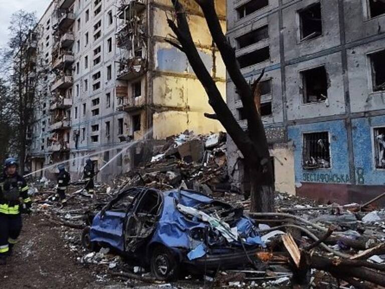 TOPSHOT - Rescuers walk past a residential building damaged after a strike in Zaporizhzhia, amid the Russian invasion of Ukraine on October 9, 2022. - An overnight Russian missile strike killed at least 12 people in Zaporizhzhia, authorities said on October 9, 2022, in the latest deadly attack to hit the southern Ukrainian city that President Volodymyr Zelensky called "absolute evil". (Photo by Maryna Moiseyenko / AFP) (Photo by MARYNA MOISEYENKO/AFP via Getty Images)