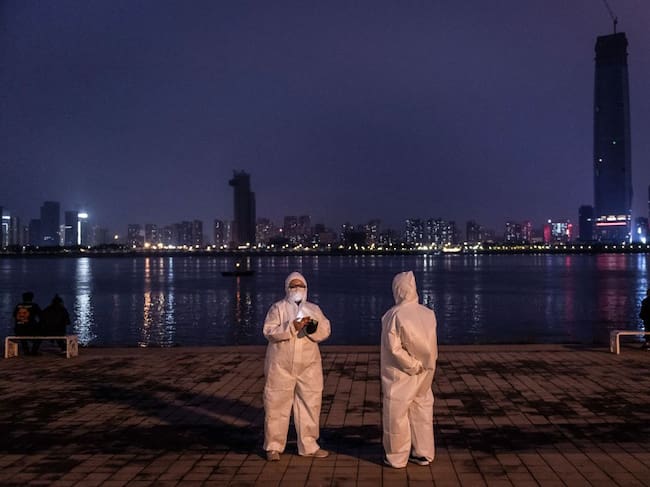 Un par de ciudadanos chinos se fotografían con trajes sanitarios en una plaza de la ciudad de Wuhan