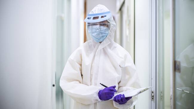 Asian doctor holding checking coronavirus or covid-19 infected patient name list sheet in quarantine area in hospital