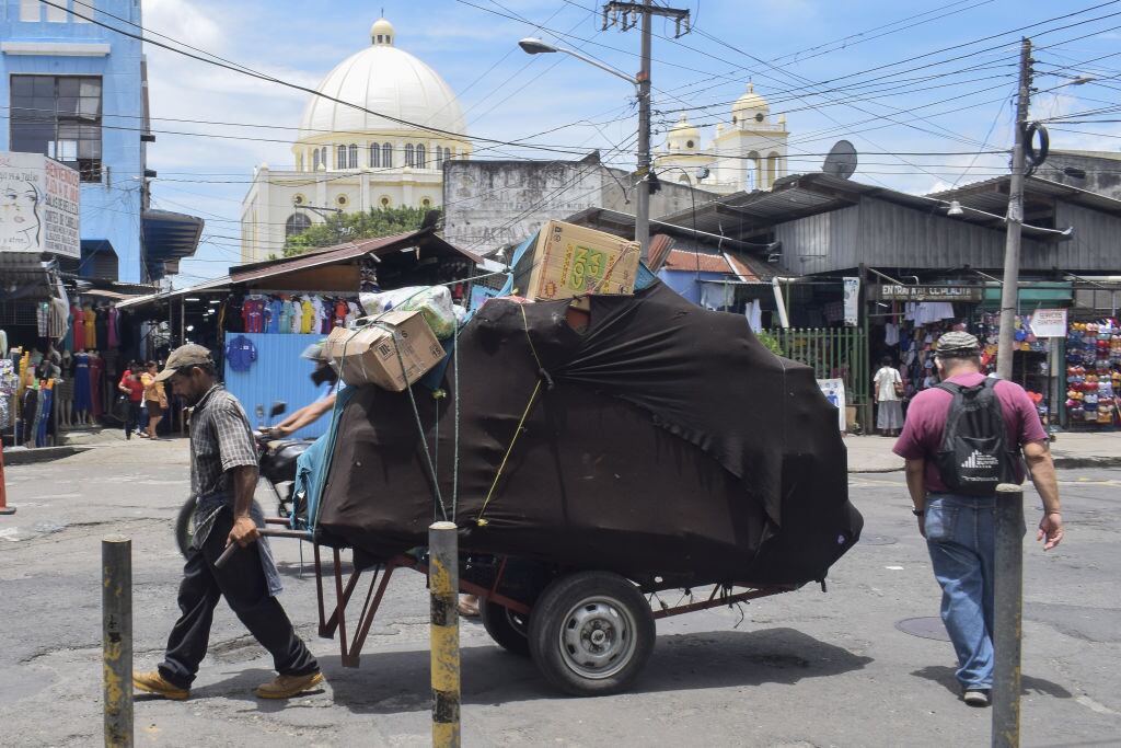 Hombre traslada una carreta en medio de cesantes en El Salvador
