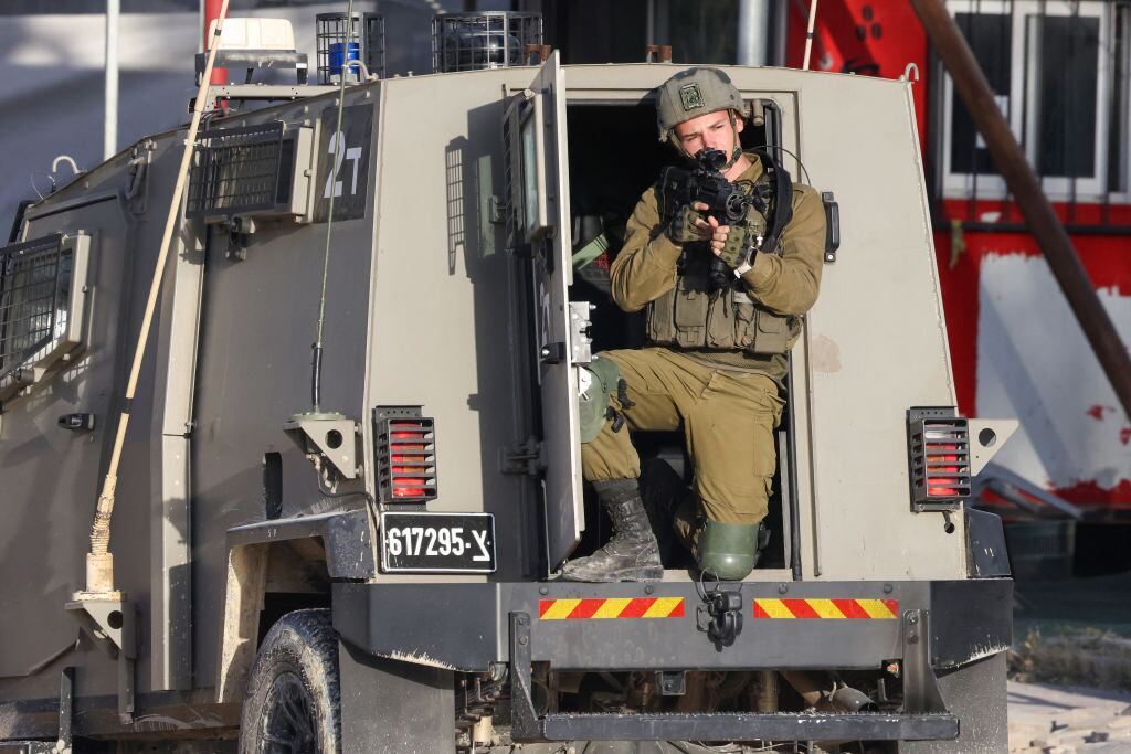 Un soldado de Israel apunta con su arma desde un vehículo blindado, en medio de un operativo en un campo de refugiados en el West Bank de Palestina.