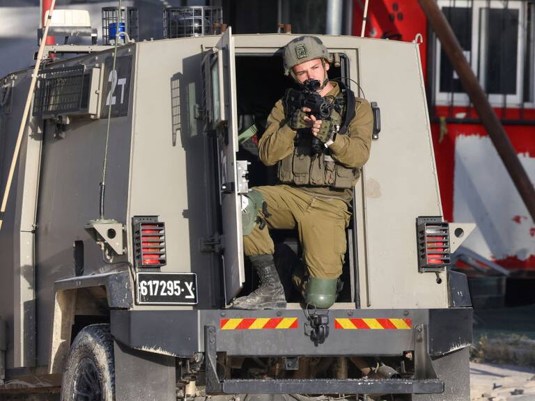 Un soldado de Israel apunta con su arma desde un vehículo blindado, en medio de un operativo en un campo de refugiados en el West Bank de Palestina.
