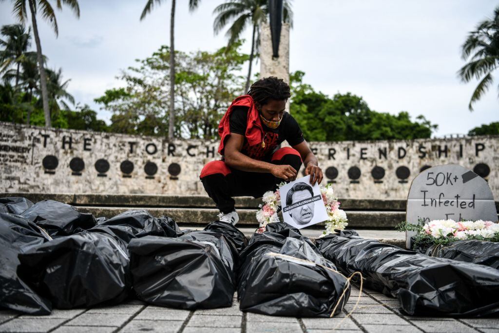 Manifestantes colocan rostros de víctimas en Covid-19 en una protesta en Miami