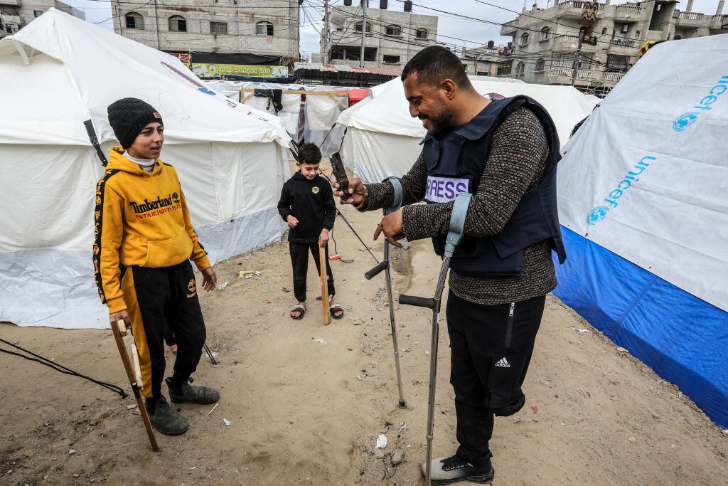 El periodista palestino Hazem Suleiman, a quien le amputaron una pierna tras un ataque de Israel, saluda a unos niños refugiados en la Franja de Gaza.