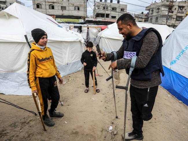 El periodista palestino Hazem Suleiman, a quien le amputaron una pierna tras un ataque de Israel, saluda a unos niños refugiados en la Franja de Gaza.