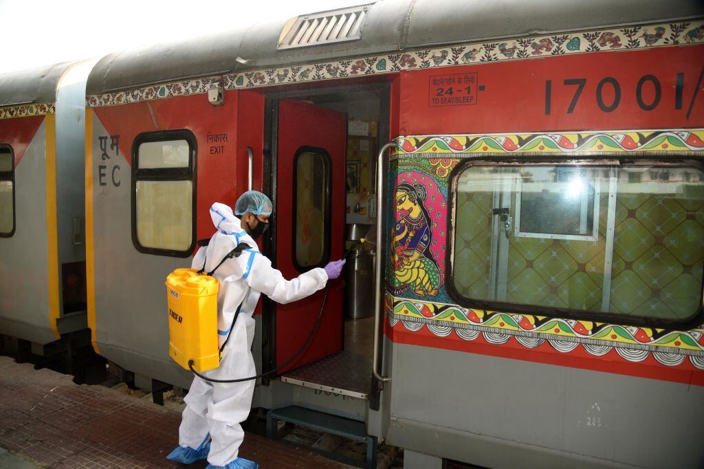 Un trabajador desinfecta el carro de un tren en India