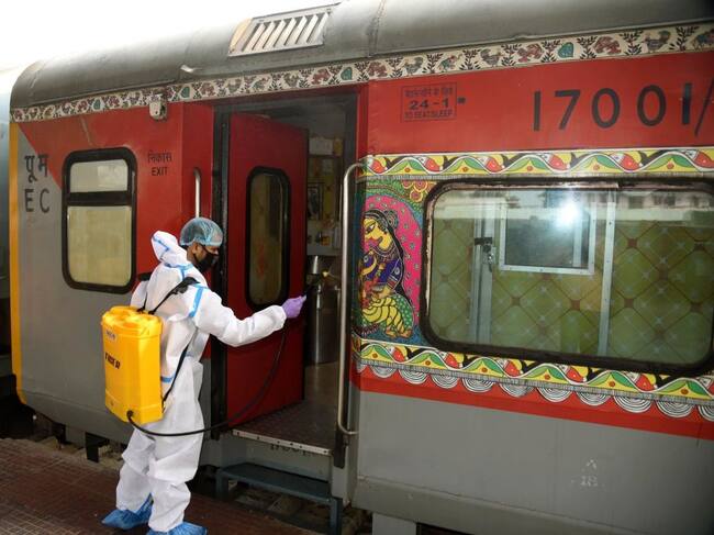 Un trabajador desinfecta el carro de un tren en India