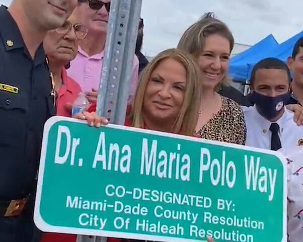 Ana María Polo posando con los ciudadanos de Hialeah y el letrero de su calle.
