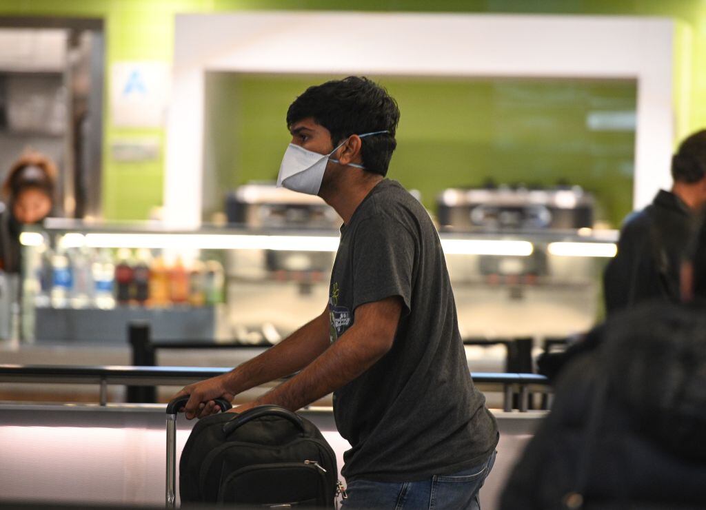 Un pasajero utiliza mascarilla mientras se desplaza al interior de un aeropuerto internacional