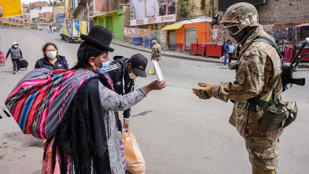 LA PAZ, BOLIVIA - MARCH 30: A military officer asks a woman for his identity card at a checkpoint on March 30, 2020 in La Paz, Bolivia. Bolivia has established a blockade to prevent the spread of COVID-19 until April 15. Only one person from each family can go out to buy supplies during the morning hours. During the weekends, everyone has to stay home. All borders have been closed. (Photo by Javier Mamani/Getty Images)