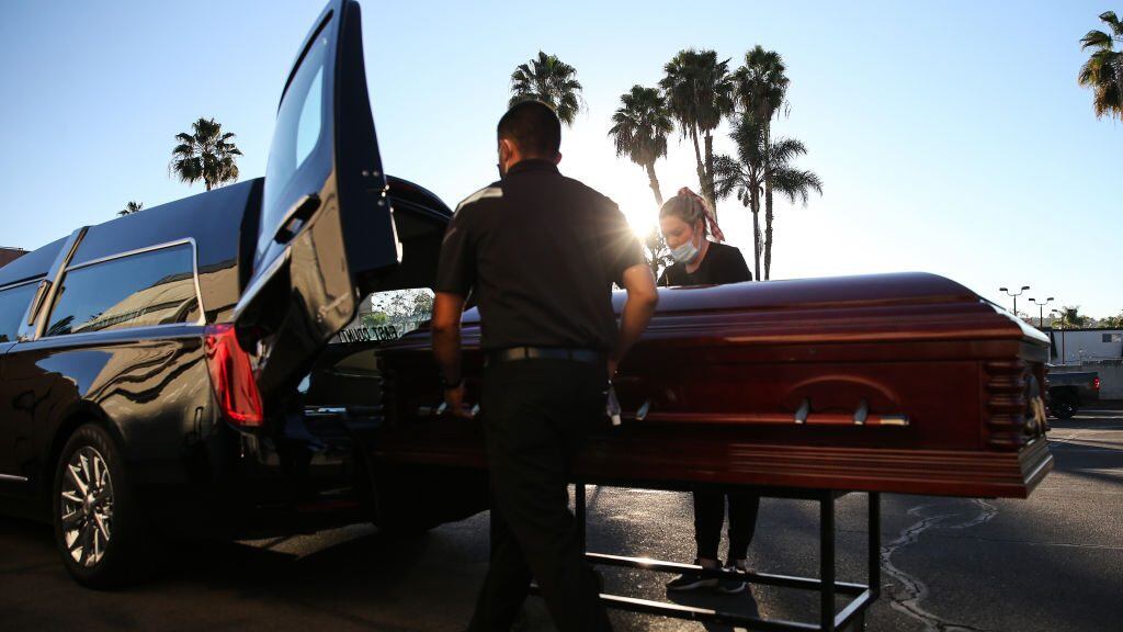 EL CAJON, CALIFORNIA - JANUARY 15: (EDITORIAL USE ONLY) Embalmer and funeral director Kristy Oliver (R) and funeral attendant Sam Deras load the casket of a person who died after contracting COVID-19 into a hearse at East County Mortuary on January 15, 2021 in El Cajon, California. The mortuary on average was handling about 50 decedents per month but owner Robert Zakar believes they may process closer to 100 in January as California continues to see a spike in coronavirus deaths. The mortuary holds the bodies of those who pass away due to COVID-19 for a minimum of three days before they are processed along with various other COVID-related safety measures. (Photo by Mario Tama/Getty Images)