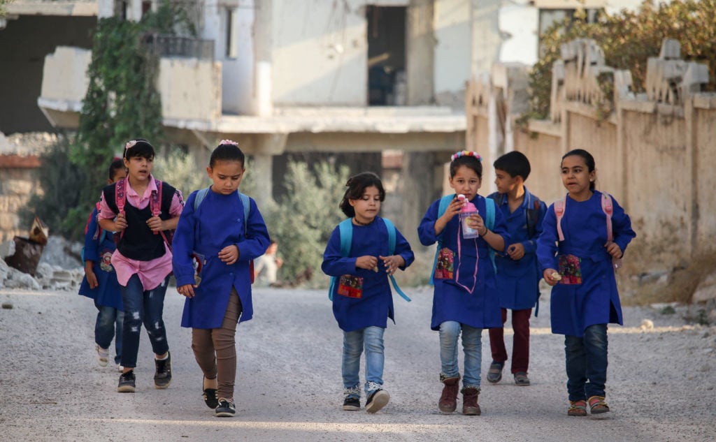 Niños caminan entre las ruinas de la ciudad de Deraa