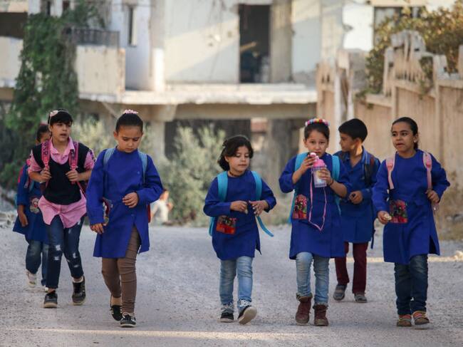 Niños caminan entre las ruinas de la ciudad de Deraa