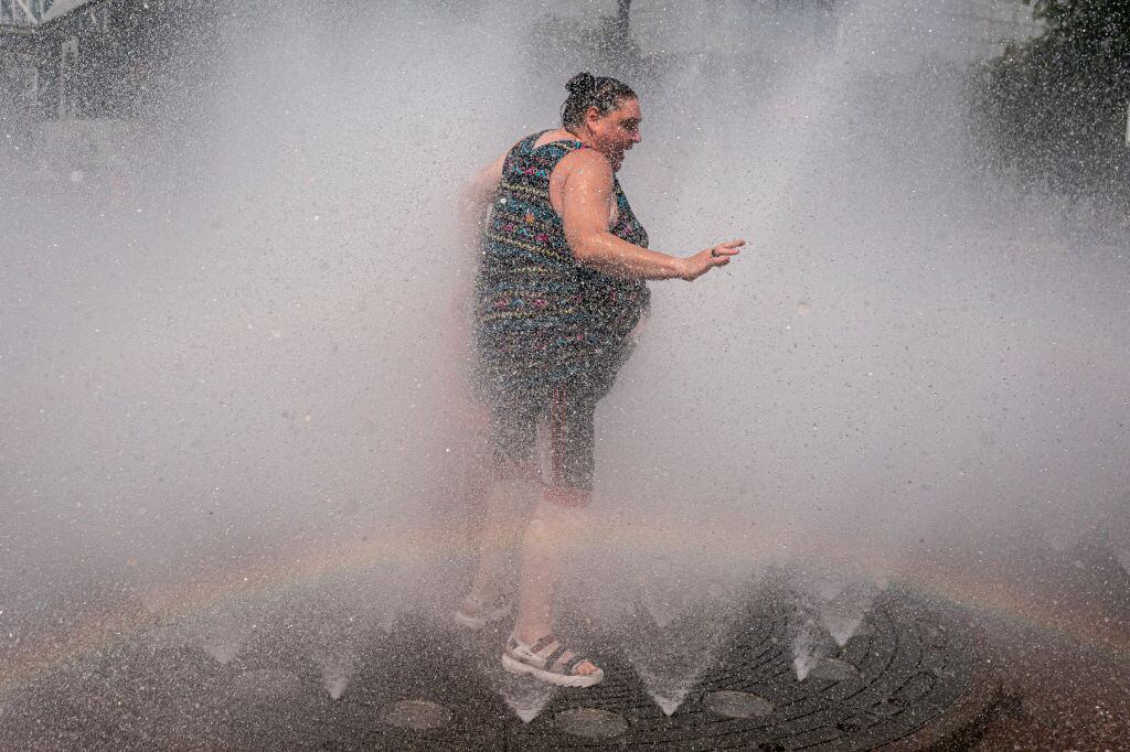 Una mujer intenta enfrentar la ola de calor en un juego de agua en Portland