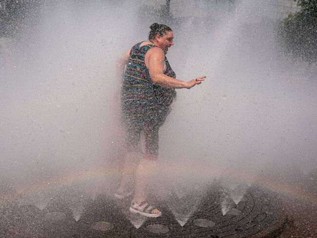 Una mujer intenta enfrentar la ola de calor en un juego de agua en Portland