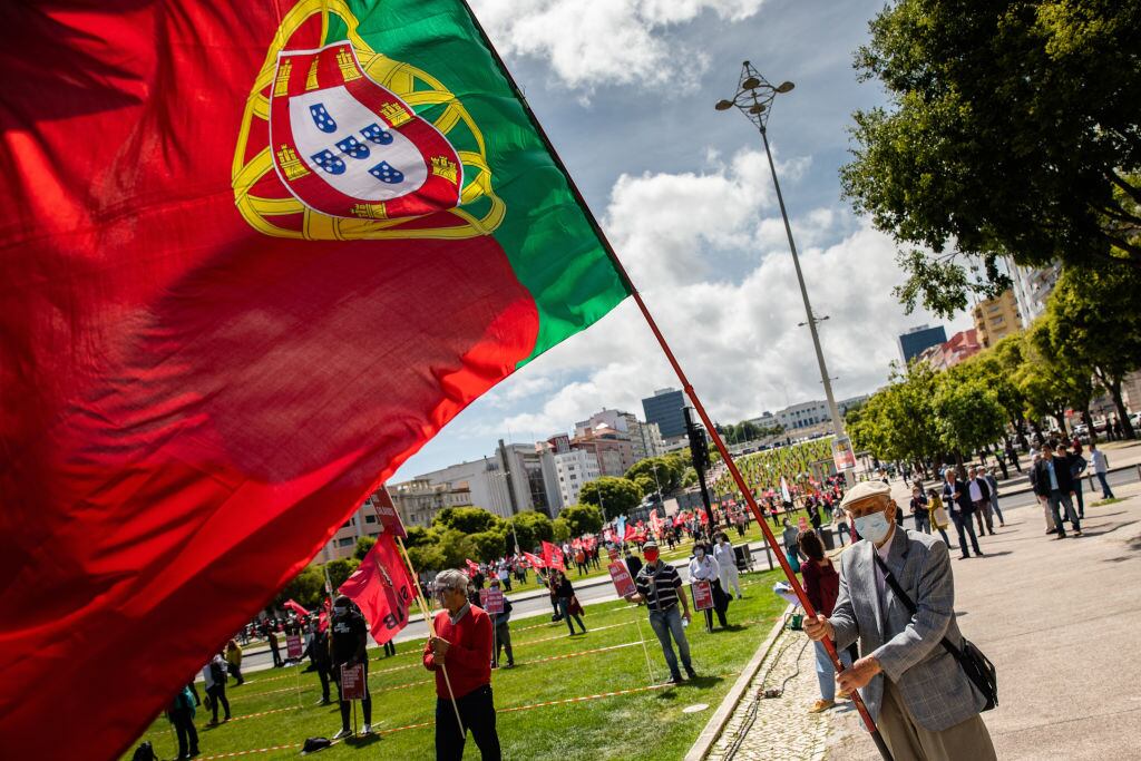 Un ciudadano con mascarilla levanta una bandera de Portugal