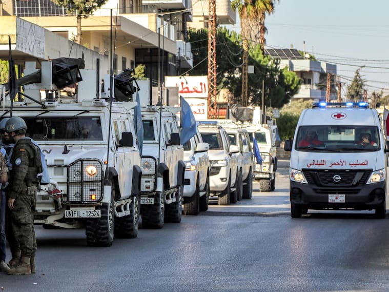 Una ambulancia de la Cruz Roja avanza al lado de un convoy de vehículos blindados de los cascos azules de la Unifil en las calles del Líbano