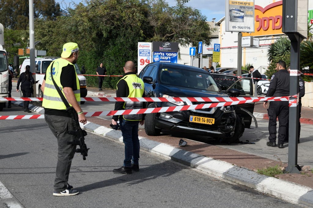 Fuerzas de seguridad de Israel resguardan la zona del ataque con un vehículo en Raanana, en donde falleció una mujer y otras 19 personas resultaron heridas.