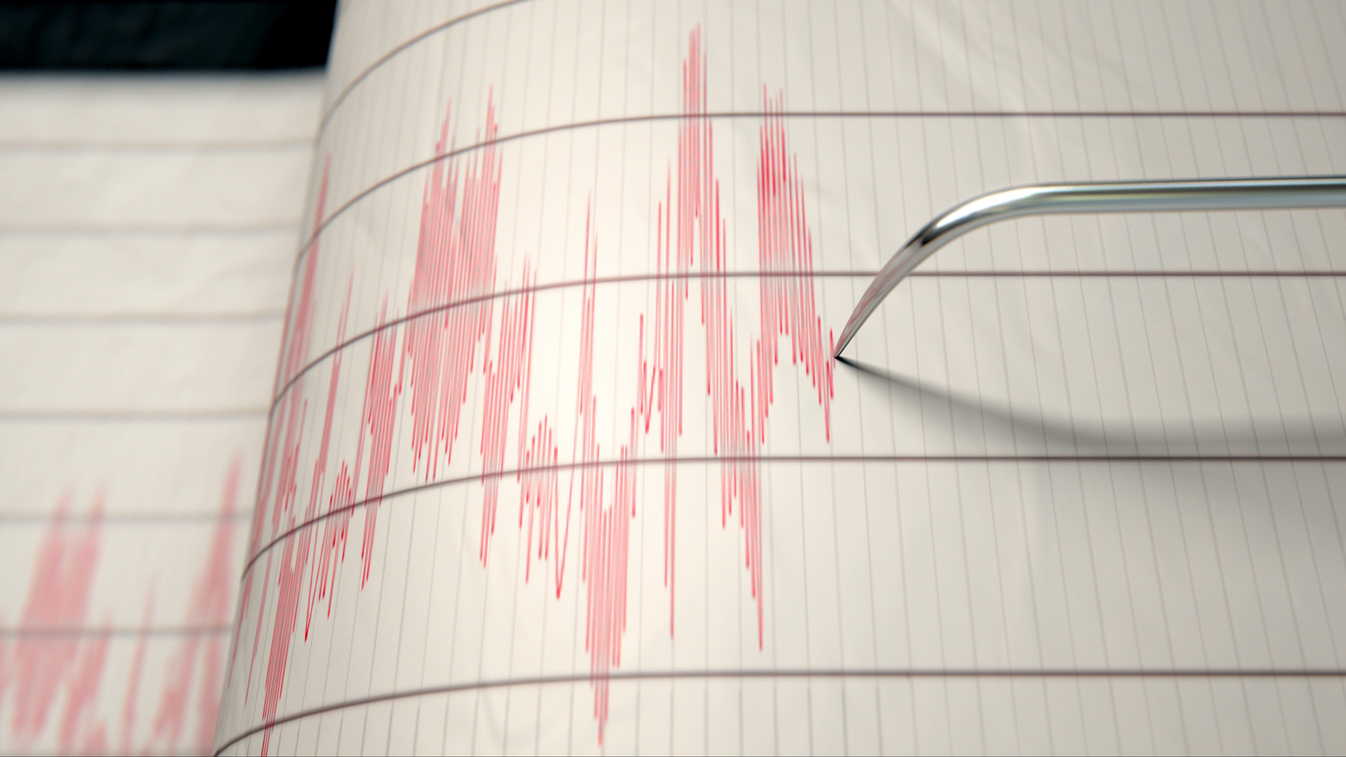 A closeup of a seismograph machine needle drawing a red line on graph paper depicting seismic and eartquake activity - 3D render