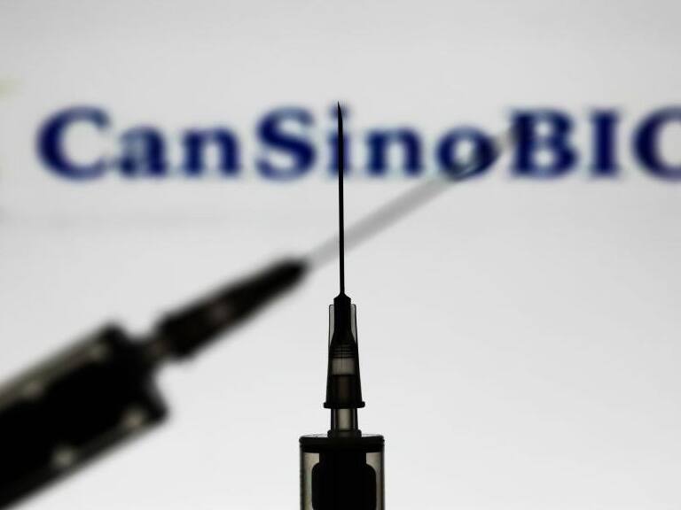 Medical syringes are seen with CanSino Biologics company logo displayed on a screen in the background in this illustration photo taken in Poland on November 15, 2020. (Photo by Jakub Porzycki/NurPhoto via Getty Images)
