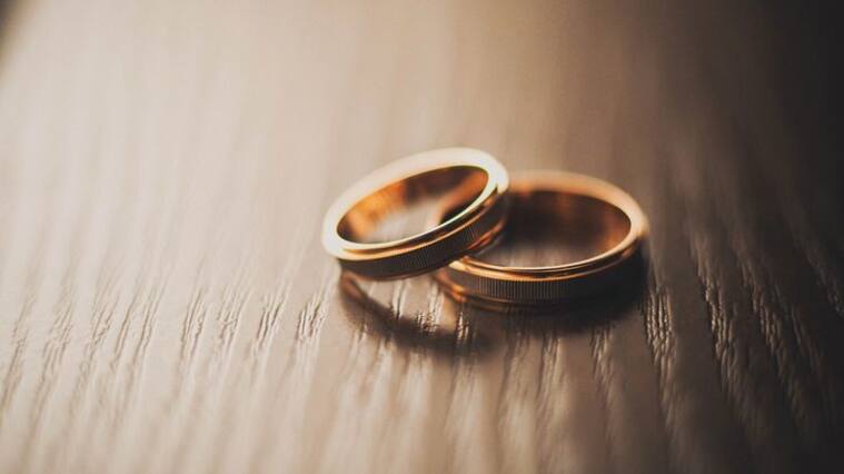 Wedding rings of the bride and groom on a wooden chest of drawers, table or bedside table.