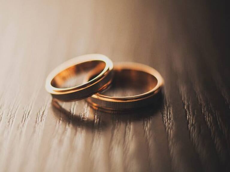 Wedding rings of the bride and groom on a wooden chest of drawers, table or bedside table.