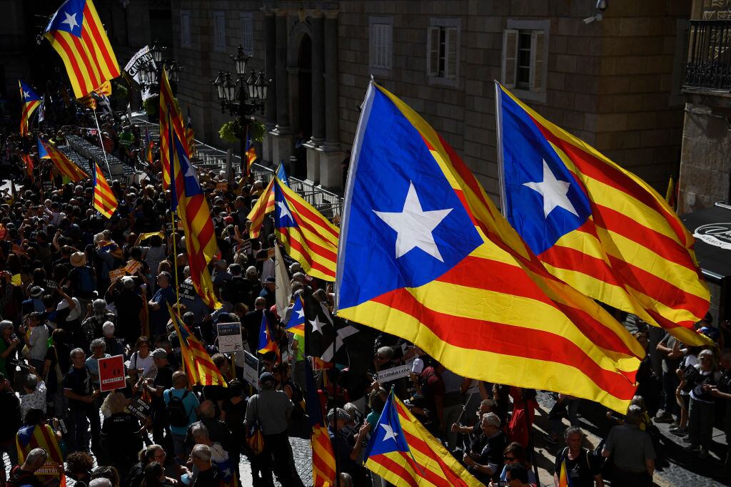 People holding Catalan pro-independence Estelada flags gather at Plaza Sant Jaume in Barcelona on October 1, 2022 to take part in a demonstration marking the fifth anniversary of a self-determination referendum organised by separatists despite being banned by the courts. - Five years after the banned referendum on independence, Catalan separatists appear to be even further from their goal of separating from Spain, with many feeling bitterly let down by their leaders. (Photo by Josep LAGO / AFP) (Photo by JOSEP LAGO/AFP via Getty Images)