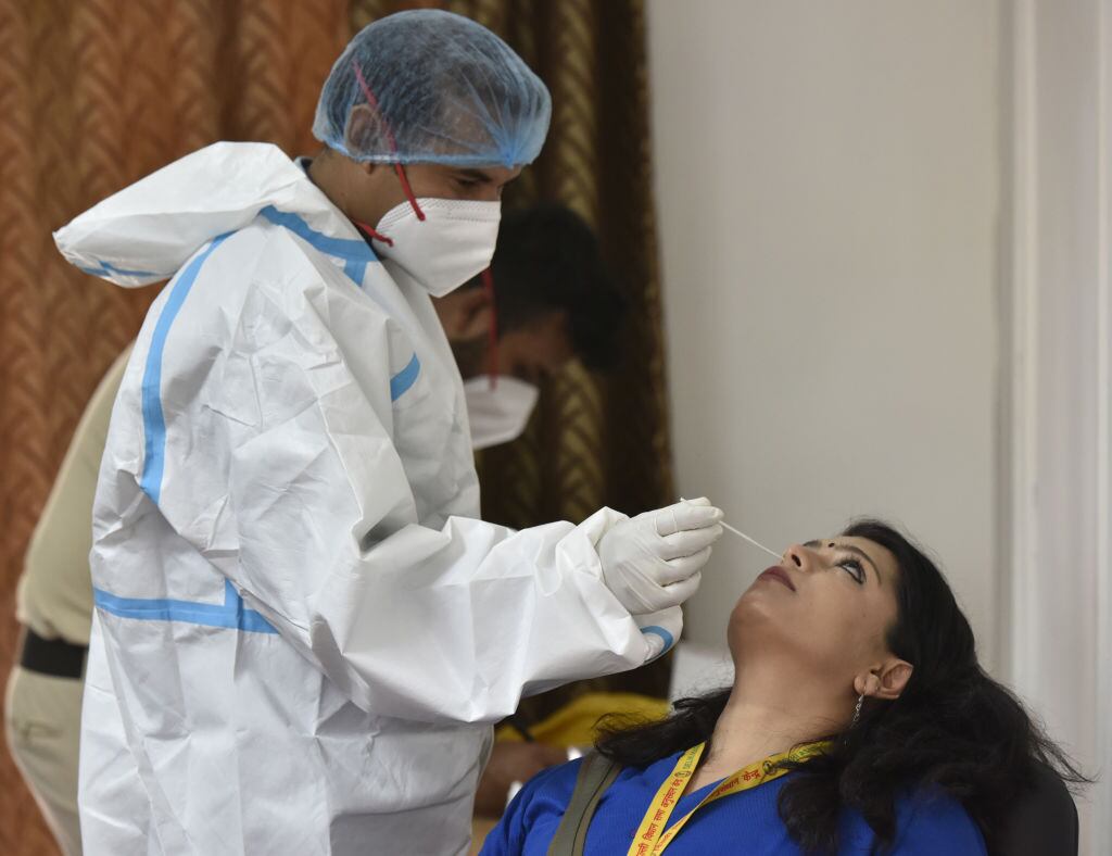 Trabajador de la salud toma un examen PCR en Nueva Delhi