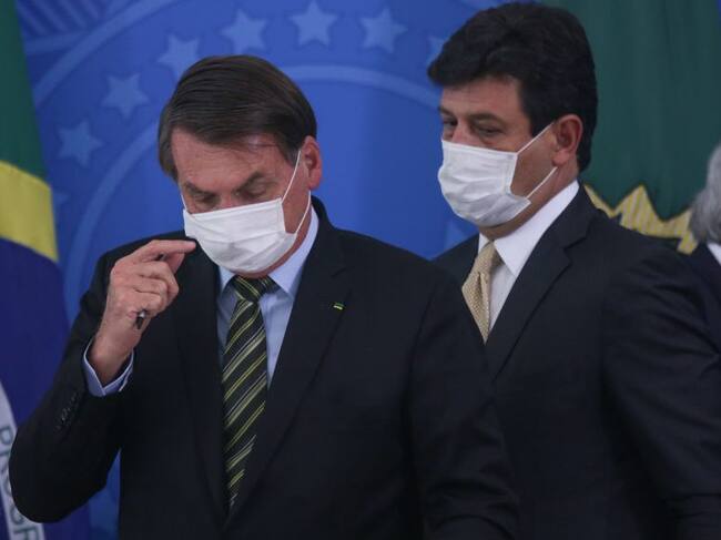 BRASILIA, BRAZIL - MARCH 18: (L-R) President of Brazil Jair Bolsonaro, Health Minister Luiz Henrique Mandetta and Economy minister Paulo Guedes wear protective masks during a press conference regarding government plans and measures about the Coronavirus (COVID-19) Outbreak in Brazil, at the Planalto Palace on March 18, 2020 in Brasilia, Brazil. (Photo by Andre Coelho/Getty Images)
