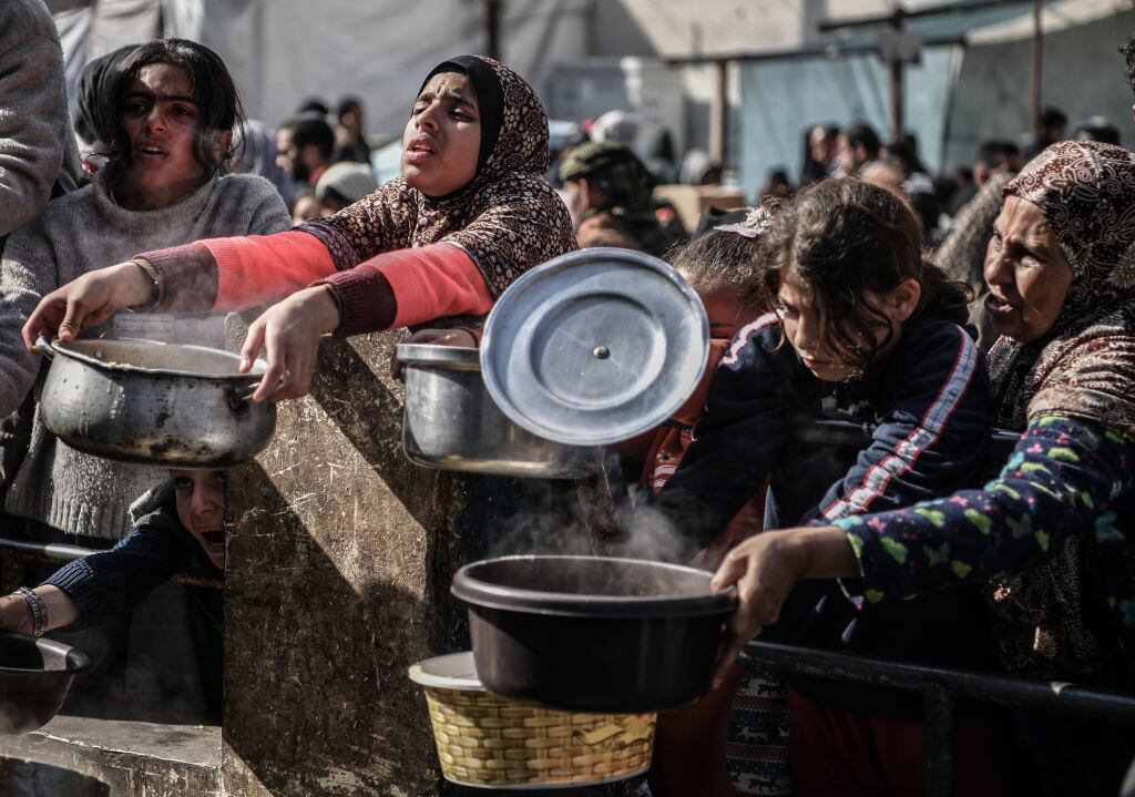 Palestinos esperan la entrega de alimentos en la Franja de Gaza, en medio de la crisis humanitaria por los ataques militares de Israel contra el enclave.