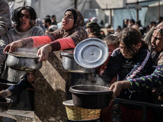Palestinos esperan la entrega de alimentos en la Franja de Gaza, en medio de la crisis humanitaria por los ataques militares de Israel contra el enclave.