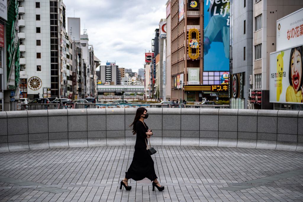 Una mujer usa mascarilla al caminar por la ciudad de Osaka