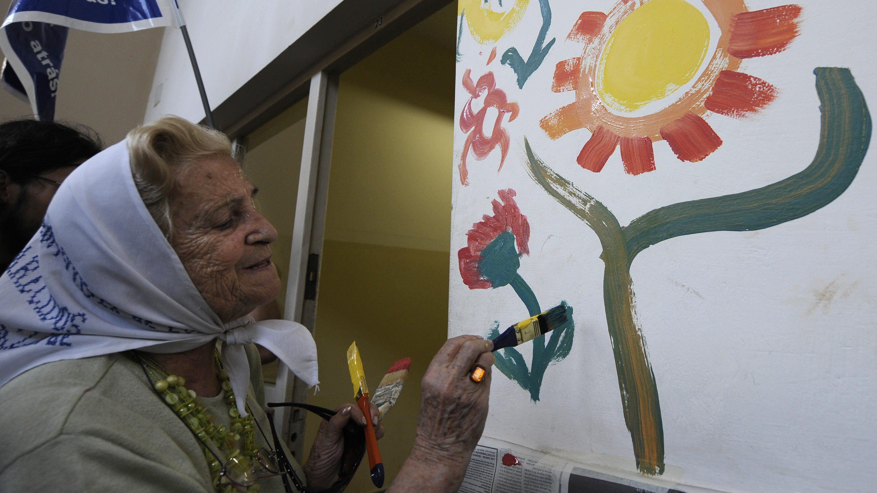 Mercedes "Porota" de Mero?o, vice president of the Madres de Plaza de Mayo organization, paints a flower on the wall of the Liceo Naval building, located inside the ESMA compound (former clandestine detention center of the Argentinian Navy during the military dictatorship) in Buenos Aires 31 January, 2008. The humanitarian organization take in charge today the building, where they will create a cultural center. AFP PHOTO/JUAN MABROMATA (Photo credit should read JUAN MABROMATA/AFP via Getty Images)