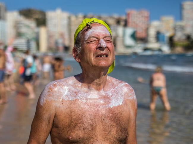 Un hombre intenta soportar el fuerte calor en una playa en Benidorm