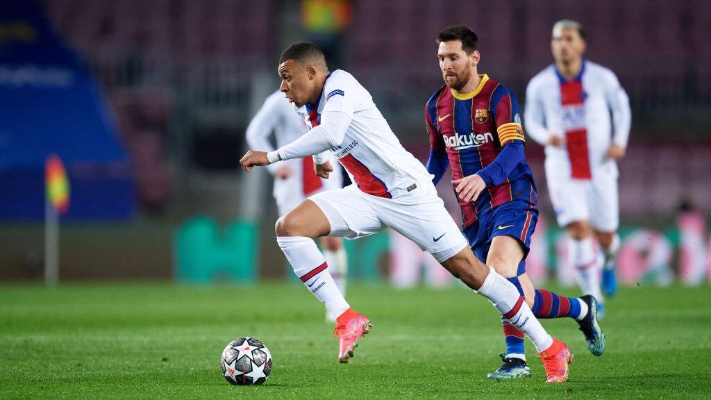 BARCELONA, SPAIN - FEBRUARY 16: Kylian Mbappe of Paris Saint-Germain runs with the ball past Lionel Messi of FC Barcelona during the UEFA Champions League Round of 16 match between FC Barcelona and Paris Saint-Germain at Camp Nou on February 16, 2021 in Barcelona, Spain. Sporting stadiums around Spain remain under strict restrictions due to the Coronavirus Pandemic as Government social distancing laws prohibit fans inside venues resulting in games being played behind closed doors.  (Photo by Alex Caparros - UEFA/UEFA via Getty Images)