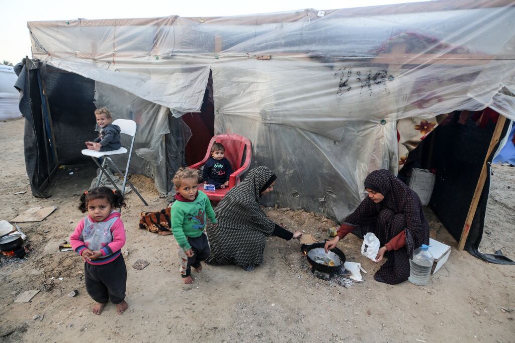 Dos mujeres palestinas preparan algo de alimento para darles de comer a cuatro niños en la Franja de Gaza en Palestina.