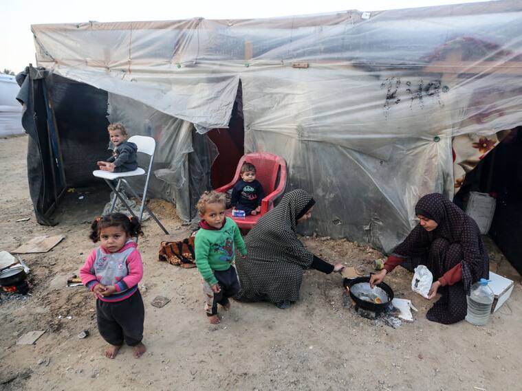 Dos mujeres palestinas preparan algo de alimento para darles de comer a cuatro niños en la Franja de Gaza en Palestina.