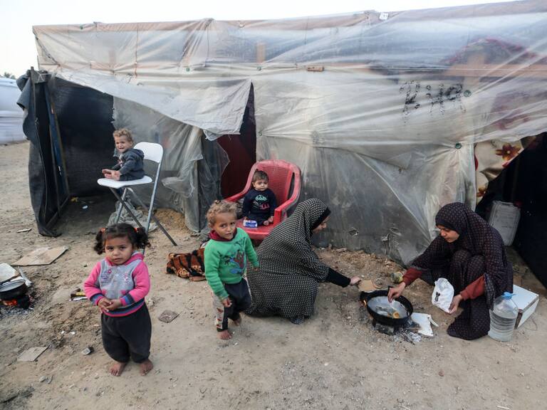 Dos mujeres palestinas preparan algo de alimento para darles de comer a cuatro niños en la Franja de Gaza en Palestina.