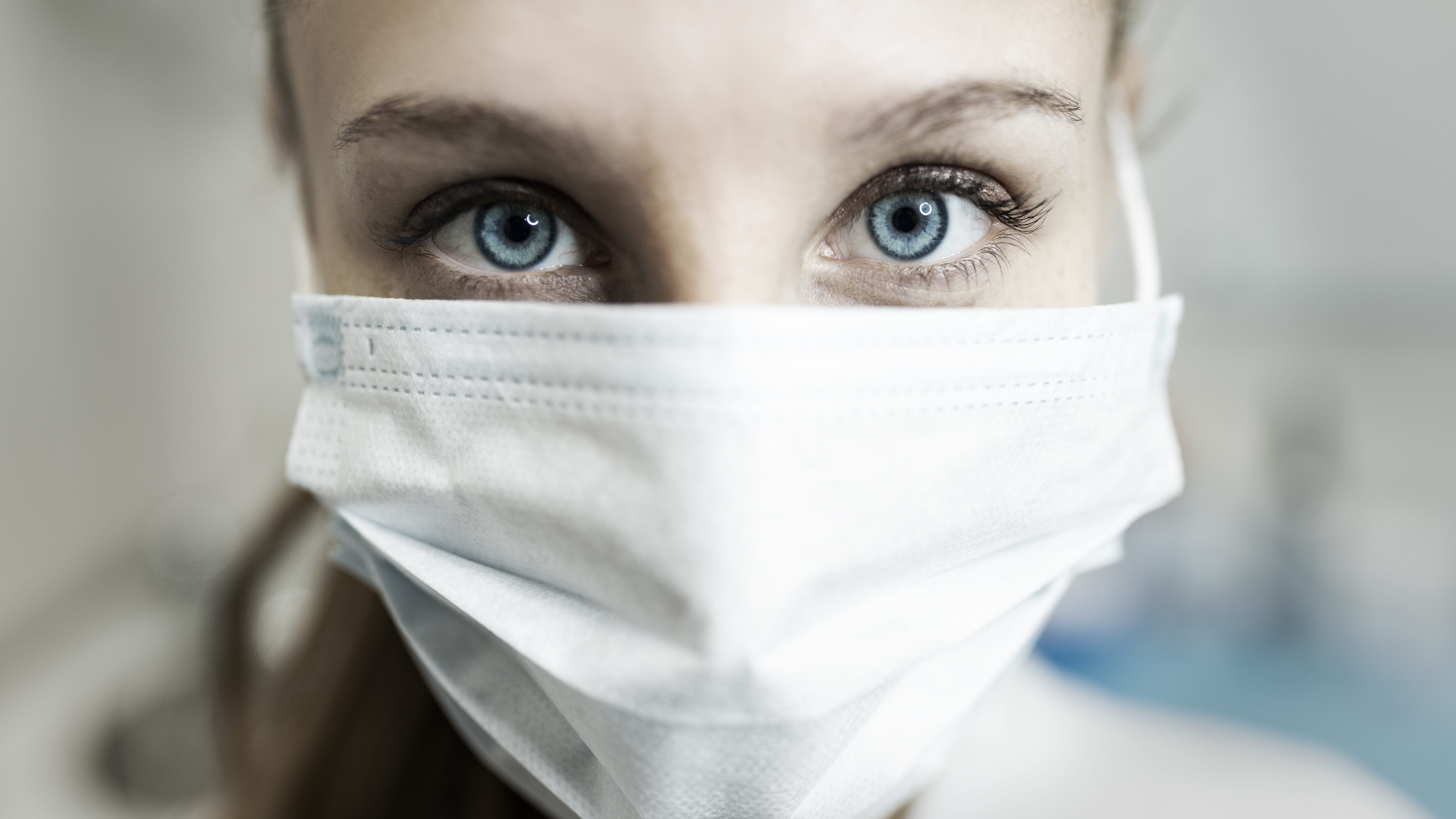 Blue-eyed nurse at her workplace wearing a protective mask.