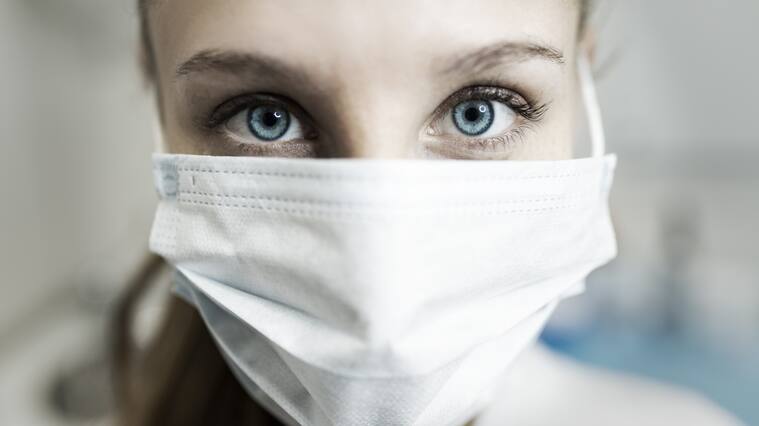 Blue-eyed nurse at her workplace wearing a protective mask.