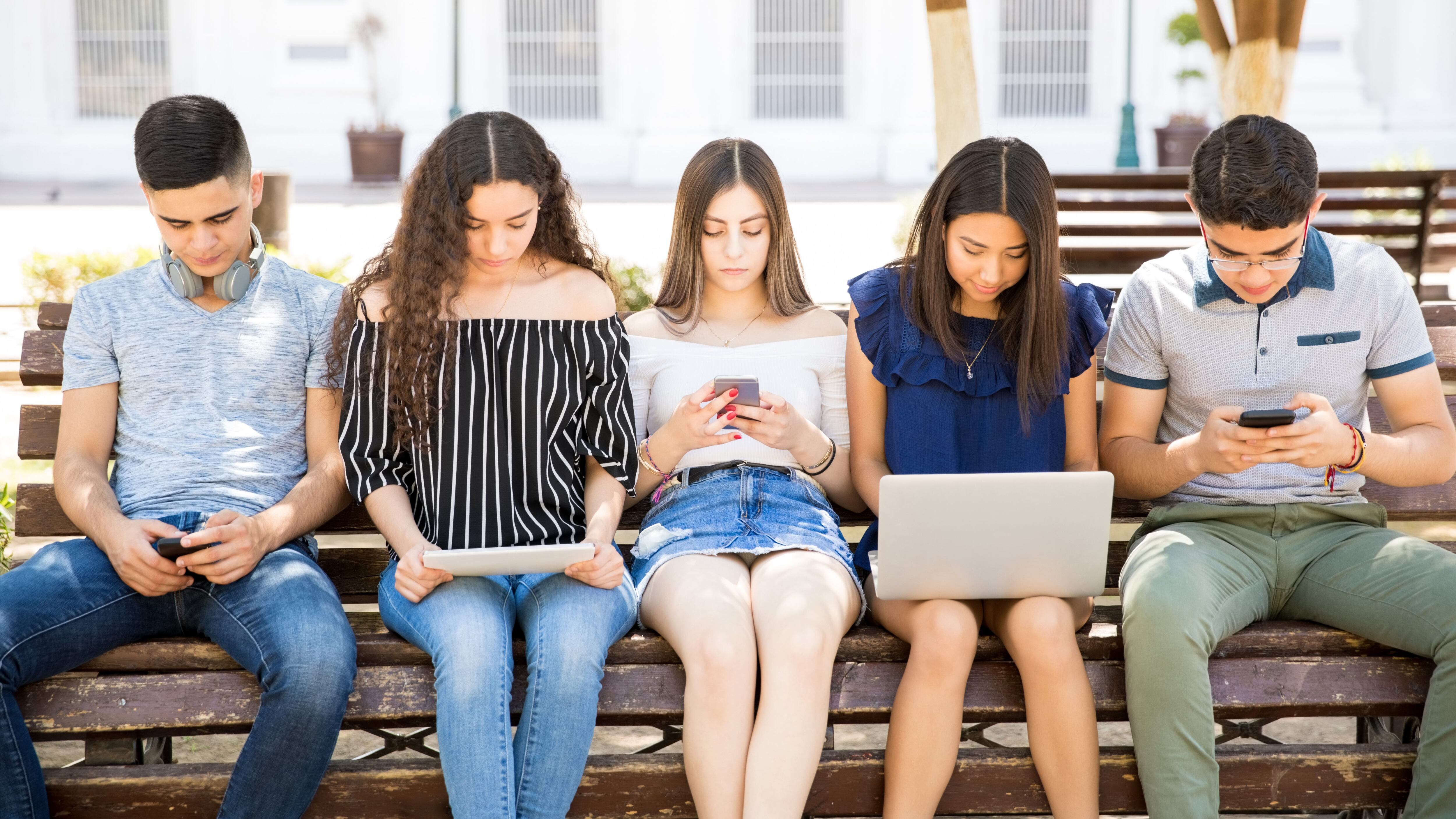 Teenage boys and girls using different devices like laptop, digital tablet and smart phone for social networking