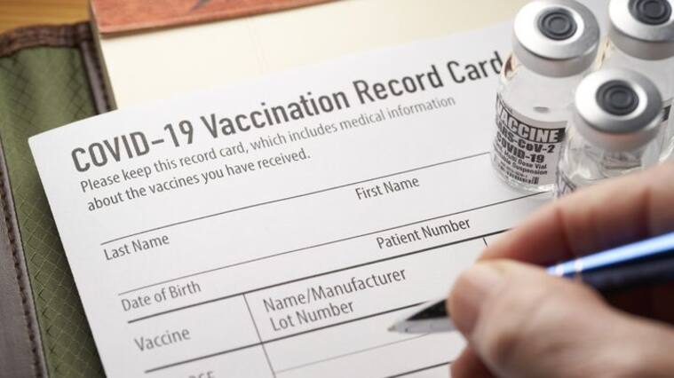 Covid-19 vaccination record card with vials and syringe. Pfizer, Moderna, Johnson & Johnson