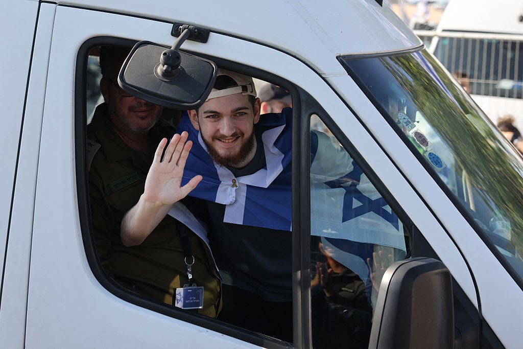 Bar Kuperstein, one of the released Israeli hostages formerly held captive in Gaza since the 2023 October 7 attacks by Palestinian militants, waves from the window of a bus at Sheba Tel-HaShomer Medical Centre in Ramat Gan on October 13, 2025. (Photo by AHMAD GHARABLI / AFP) (Photo by AHMAD GHARABLI/AFP via Getty Images)          