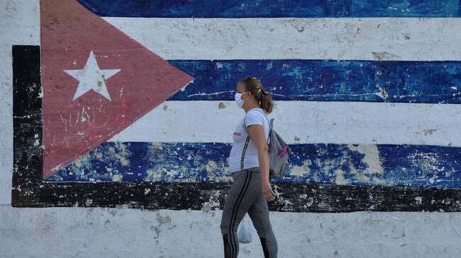 Una mujer utiliza una máscara mientras camina por la ciudad de La Habana